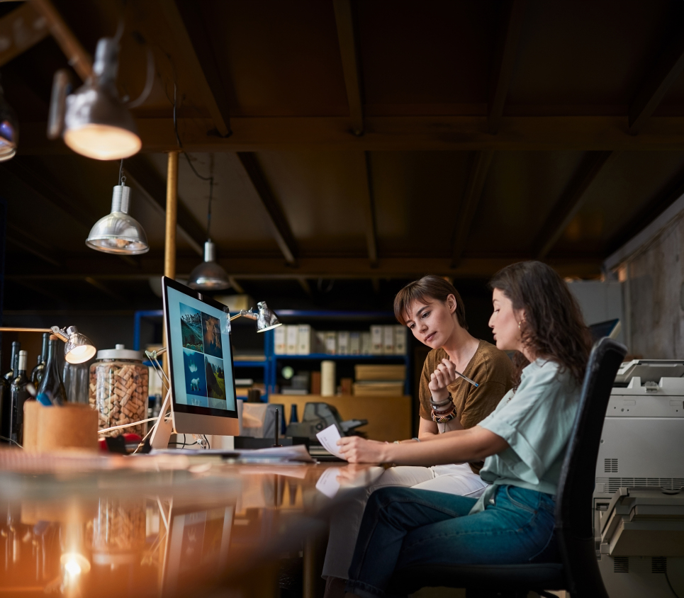 Dos compañeras de trabajo en oficina moderna revisando proyectos, representando el bienestar laboral que ofrece el seguro de salud DKV PYMES Integral.